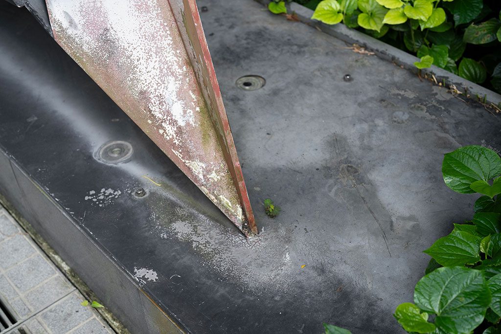 Before — base detail showing flaking paint and surface corrosion